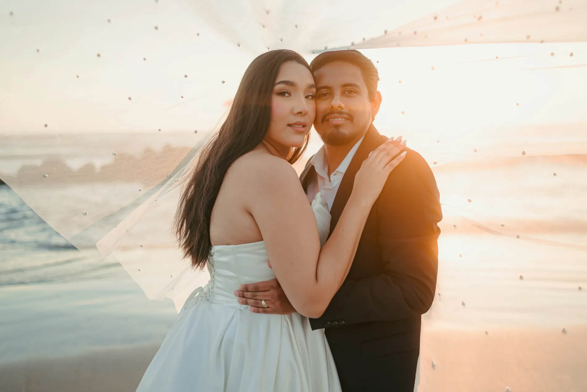 Paulina y Andrés abrazados, el mar detrás al atardecer