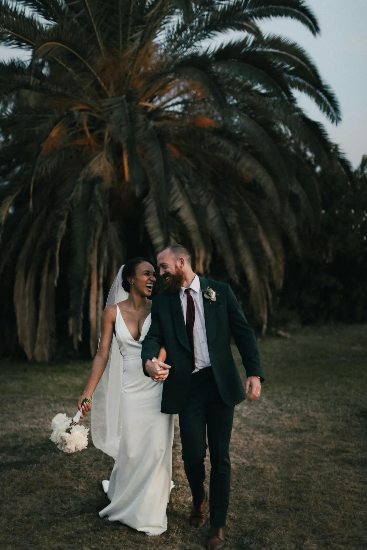 Renata y Diego caminando bajo las palmeras de la hacienda